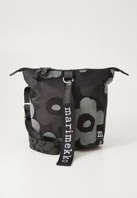 Borsa a secchiello in tessuto nero con grandi motivi floreali grigi. Caratterizzata da una chiusura con cerniera, tracolla regolabile con marchio e superficie strutturata.