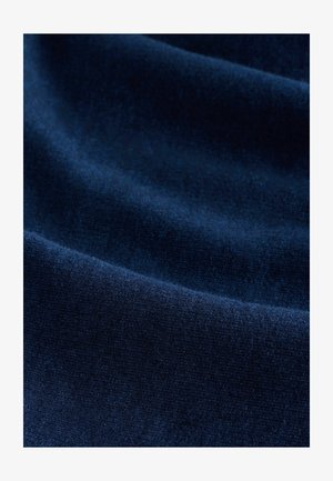 Tissu en velours bleu foncé avec de doux plis et une texture lisse et moelleuse créant des ombres et des reflets doux.