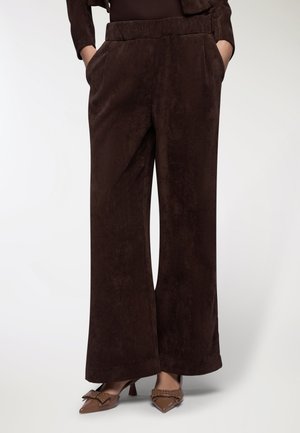 Pantaloni a gamba larga in corduroy marrone con superficie testurizzata, dotati di tasche laterali e vita elasticizzata, abbinati a tacchi a punta marroni.