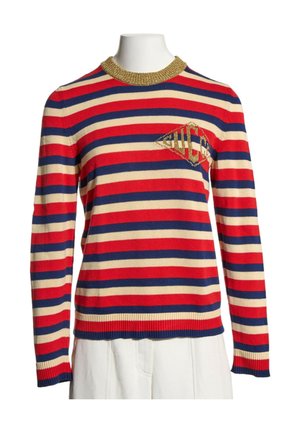 Pull à manches longues avec des rayures horizontales rouges, bleu marine et crème, col côtelé doré et logo doré en forme de diamant sur la poitrine.