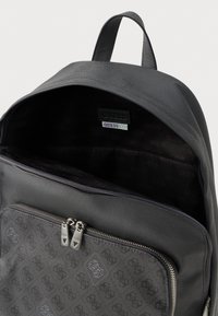 Juodas kuprinė su tekstūruotu paviršiumi, su užtrauktuku priekinėje kišenėje ir raštuota pamušalu. Turi viršutinį rankeną ir vidinę etiketę su ženklu.