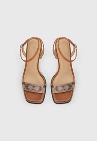 Καφέ δερμάτινα σανδάλια με τακούνι, τετράγωνη μύτη και στενούς ιμάντες στον αστράγαλο. Διαθέτουν υφασμάτινη ζώνη με σχέδιο στο μπροστινό μέρος. Ομοιόμορφη υφή σε όλη την επιφάνεια.