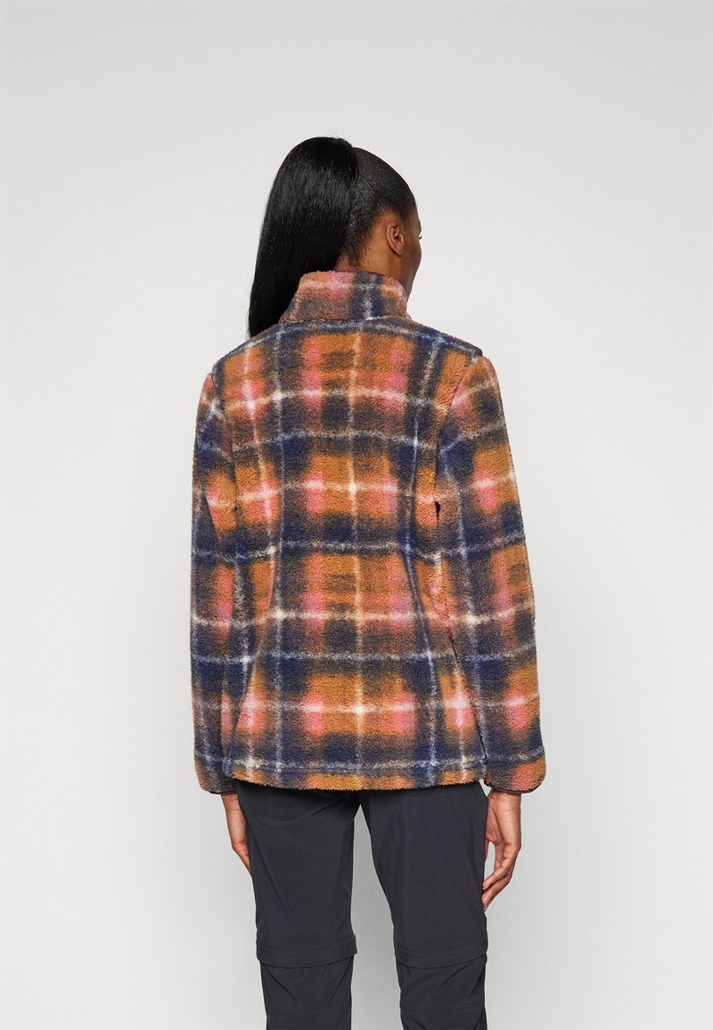 Veste en polaire à motif écossais avec des teintes orange, bleu et rose. Elle présente un col haut et une texture douce, avec des poches latérales.