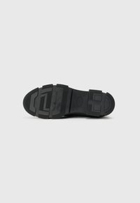 Suela de zapato de goma negra con una superficie texturada, diseño segmentado y varios acentos geométricos para agarre y soporte.