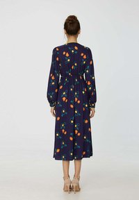 Robe fleurie navy avec taille élastique, manches longues et longueur mi-mollet. Décorée de motifs floraux orange et verts.