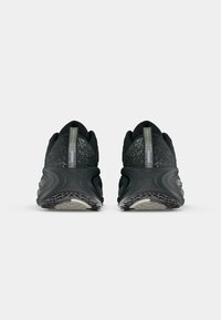 Ein Paar schwarze und graue Laufschuhe, von hinten gezeigt, mit strukturierten Sohlen und Zugschlaufen, die mit "NIKE INTL." beschriftet sind.