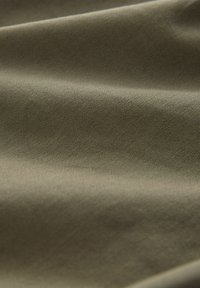 Olive green fabric with a smooth, slightly textured surface, showcasing fine diagonal ribbing and subtle sheen in draped folds.
