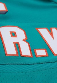 Maillot turquoise avec des lettres blanches brodées et des contours orange. Tissu texturé avec une finition lisse et des accents contrastés.