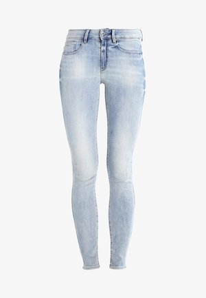 Svijetloplave uske traperice s izblijedjelim završetkom, dizajn s pet džepova i patentni zatvarač. Sadrži bešavna pojas i uski kroj.