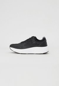 Svart atletisk sneaker med hvit polstret såle, mesh-overdel, snøring og polstret hælkollarbånd på ensfarget lysegrå bakgrunn.