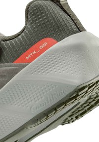 Κλείσιμο εικόνας της φτέρνας αθλητικού παπουτσιού σε πράσινο και γκρι χρώμα με υφή λευκής σόλας που φέρει την ένδειξη «ComfiRide» και κόκκινη ετικέτα «MTK_001».
