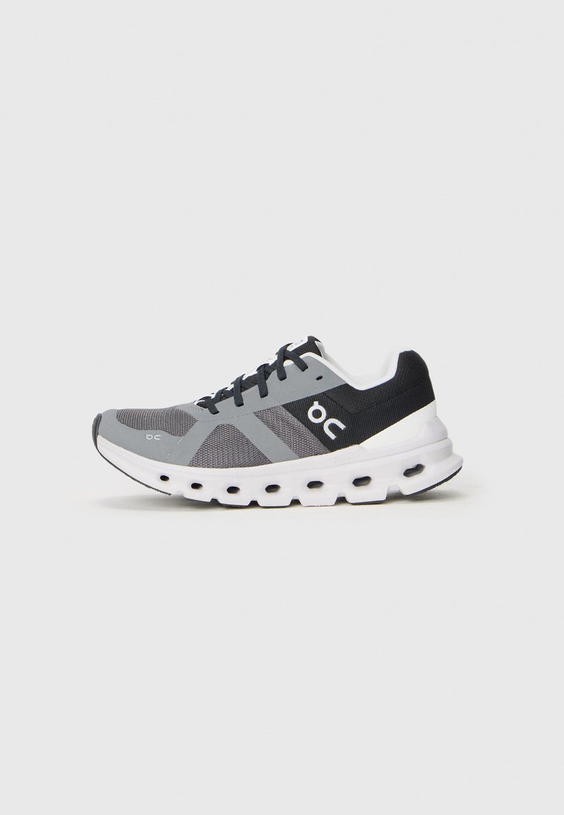 Grau und schwarze Laufschuhe mit weißer Sohle, die Belüftungslöcher und schwarze Schnürsenkel aufweisen, seitlich auf einem weißen Hintergrund dargestellt.
