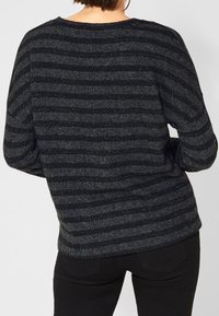 Randig tröja i svart och grått med mjuk textur, prydd med metallictrådar. Lätt lös passform med rund halsringning och nedfallna axlar.