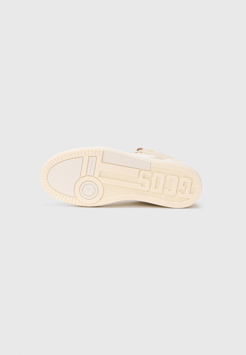 Shoe sole in beige with textured grip patterns, featuring a circular accent and brand logo embossed on the side.