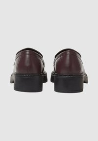 Scarpe in pelle color bordeaux scuro con finitura liscia, tacco nero basso e bordi arrotondati sulla parte superiore. Design semplice senza motivi visibili o dettagli in metallo.