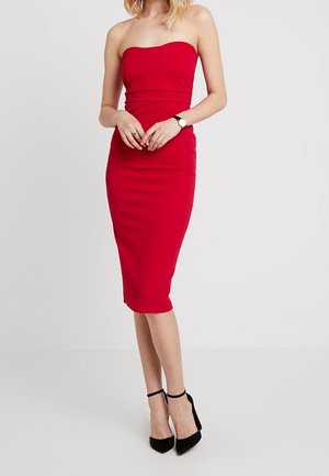 Rotes, schulterfreies, figurbetontes Kleid in Midi-Länge mit glatter Textur und einem strukturierten Oberteil. Tragend mit schwarzen Riemchen-Absätzen.
