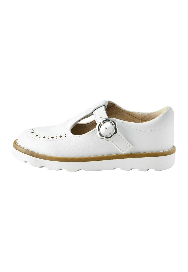 Chaussure T-bar en cuir blanc avec des perforations, bride réglable, bout rond et semelle en caoutchouc avec un accent marron autour du bord.