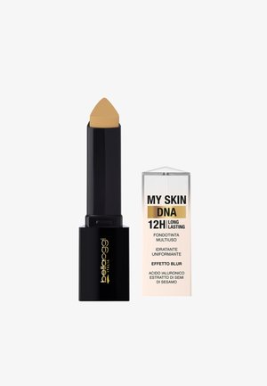 Fondotinta stick con punta beige appuntita e custodia nera accanto a una scatola trasparente etichettata "My Skin DNA 12H Long Lasting" in italiano.