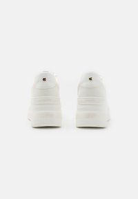 Ein Paar weiße Plateausneaker mit ALDO-Branding an der Ferse, von hinten vor einem schlichten weißen Hintergrund betrachtet.