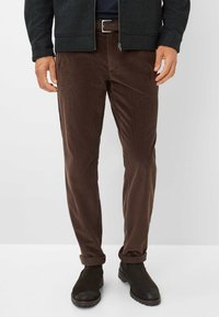 Bruine corduroy broek met een rechte pasvorm, voorzien van subtiele ribbels, een riem met een zilveren gesp en opgerolde manchetten, gecombineerd met zwarte enkellaarzen.