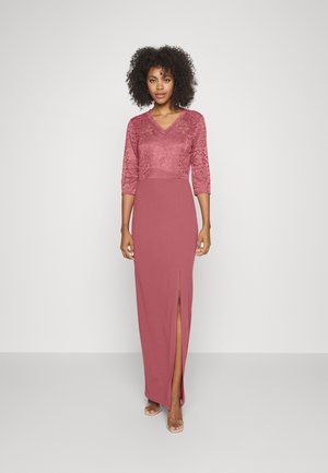 Vestido maxi em mauve com parte superior em renda, decote em V e mangas três quartos. A racha frontal revela a perna, saia inferior lisa.