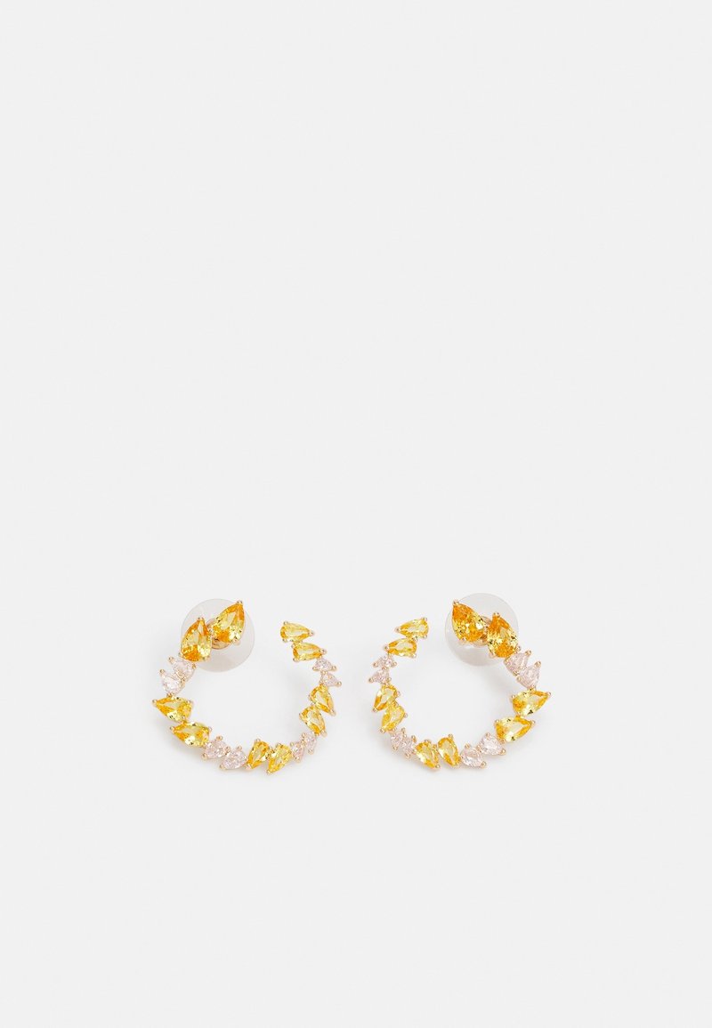 Boucles d'oreilles créoles ornées de pierres précieuses en forme de goutte alternant jaune et rose clair sur fond blanc.