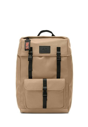 Beige Canvas-Rucksack mit einer Frontklappen-Tasche, schwarzer Hardware, verstellbaren Riemen und einem oberen Tragegriff. Mit einem Logopatch.