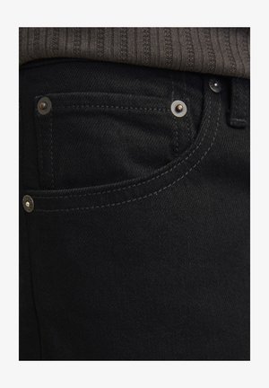 Czarne dżinsy o slim fit z gładką fakturą. Posiadają srebrne elementy, nity i kontrastowe przeszycia w okolicach kieszeni.