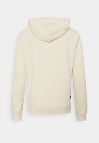 Krémová mikina s kapucí na stahovací šňůrku, dlouhými rukávy, žebrovanými manžetami a uvolněným střihem. Vyrobena z jemné, hladké látky bez vzorů.