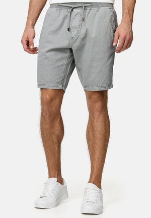 Shorts gris clair en coton, avec une taille élastique et un cordon de serrage, des poches latérales et une coupe droite. Une paire de baskets blanches est visible.