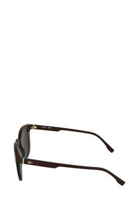 Bordowe okulary przeciwsłoneczne z ciemnymi soczewkami, prostokątną oprawką, zielonym akcentem przy zawiasach oraz złotym logo po boku. Smukły design.