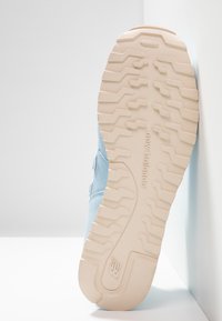 Baskets bleu clair avec une tige en daim texturé et une semelle en caoutchouc crème présentant un motif de traction multi-directionnel.