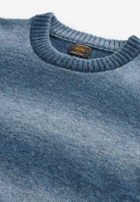 Blau verlaufender Strickpullover mit einem gerippten Rundhalsausschnitt, weichem Textil und einem Etikett mit Logo. Auffällige Farbtöne von Marineblau und hellerem Blau.