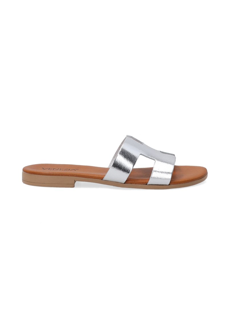Silver metallic slide sandal with two cut-out straps, tan footbed, and flat rubber sole. Smooth texture with minimalist design.