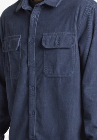 Camisa de algodón de náutica con rayas verticales, dos bolsillos en el pecho, cierre de botones y textura suave. Diseño entallado con cuello clásico.