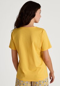 Geel katoenen T-shirt met korte mouwen en een ronde halslijn, met een gladde textuur en een ontspannen pasvorm aan de achterkant.