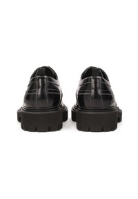 Zapatos de cuero negros con un acabado brillante, suelas gruesas apiladas y acentos de costura blanca. Presentan tiradores en el talón.