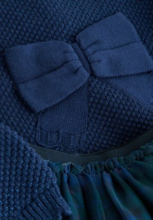Navyfarbener Strickoberteil mit strukturiertem Muster und großem Schleifendetail. Der Saum ist fransig mit geschichtetem dunkelblauem Stoff und elastischem Bund.