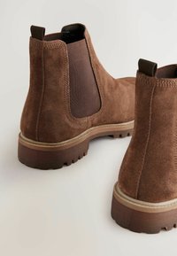 Brown suede Chelsea boots with elastic side panels, a low-cut design, textured surface, and contrasting rubber soles.
