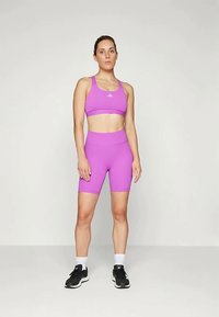 Lila sportmelltartó és hozzáillő, magas derekú sort, sima anyagból készült. Minimalista dizájnnal rendelkezik, logókkal kiemelve.