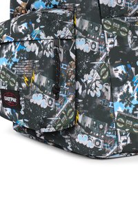 Černý batoh s grafickým potiskem, který zobrazuje boomboxy, mraky a palmy. Obsahuje přední kapsu se zipem a značkovou nášivku.