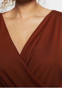 Brązowa sukienka o kroju kopertowym z dekoltem w kształcie litery V, wykonaną z miękkiego, teksturowanego materiału, z płynącą linią, podkreślająca czyste linie i elegancką sylwetkę.