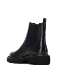 Stivale Chelsea in pelle nera con pannelli elastici sui lati, una suola in gomma nera robusta e una linguetta a ciclo sul retro. Finitura liscia.