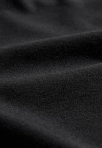 Fekete szövettel, amelynek felülete sima, enyhén texturált. A szövés szorosan összefonódik, egyenletes megjelenést teremtve, bizonyos területeken finom fényességgel.