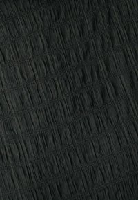 Tejido negro texturizado que presenta un diseño arrugado y recolectado con líneas verticales. El material parece ligero con un sutil brillo.