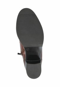 Zapato de cuero marrón con una suela de goma negra texturizada, con una forma curva y un detalle de costura mínimo. Tacón trasero con un lazo para mayor facilidad al calzar.