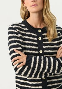 Knitted cardigan featuring navy and cream horizontal stripes, ribbed neckline and cuffs, with gold buttons along the front for closure.