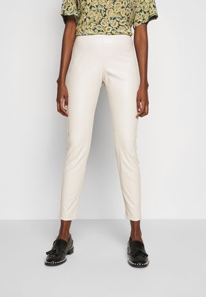 Skræddersyede beige bukser i imiteret læder med en glat overflade, der har et slankt fit og en høj talje, kombineret med en mønstret grøn top.