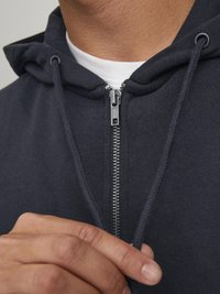 Dunkelblaue Zip-Hoodie aus weichem Material, mit silbernem Reißverschluss und verstellbaren Kordeln an der Kapuze. Nahaufnahme.