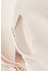 Lichtroze stof met een gladde textuur heeft een uitgesneden detail en een iets geplooide sectie, wat een contour geeft.